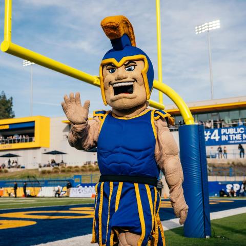 person in an oversized Trojan costume standing near end zone goal posts