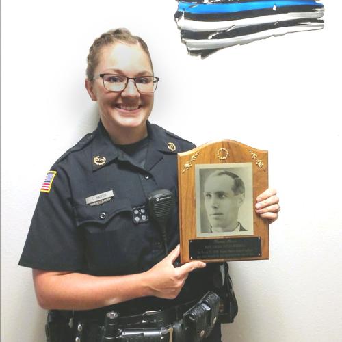 woman polic officer in uniform hold up and plaques with a photo of her ancestor Harris