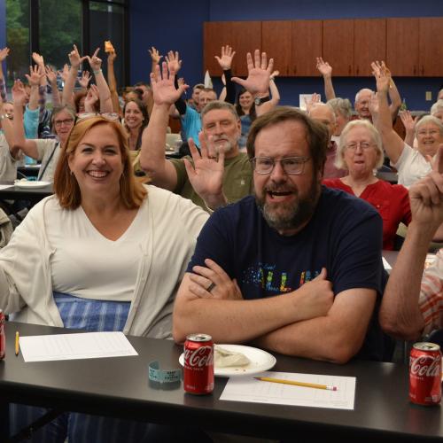 Classroom filled with people smiling and waving their hands in the air