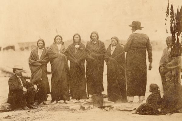Sicangu (Brule) Lakota Sioux and Oohenonpa (Two Kettle) Lakota Sioux men and women and an interpreter gathered at Fort Laramie for the 1868 treaty signing. From left to right: Leon Palladay (interpreter), Fast Bear, Spotted Tail, White Eyes, Swift Bear, Whirlwind Soldier, Long Mandan, unidentified child, The Mule's wife, Big Partisan's daughter. Sherman collection of Gardner photographs; NMAI.