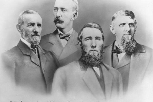 Portrait of four men in suits, each with moustache and/or beard