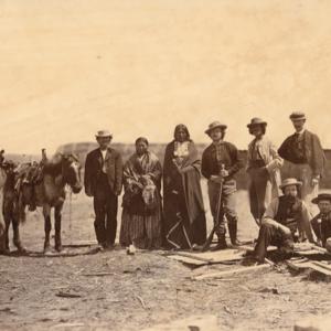 Lakota Sioux men and non-Indians gathered at Fort Laramie for the 1868 treaty signing. From left to right they are: unidentified non-Indian man; Leon Pallardy (interperter); unidentified Native woman; Running Water (Lakota); two unidentified non-Indian men; John D. Howland, (seated); Peace Commission Secretary Ashton S. H. White; and unidentified non-Indian man. Sherman collection of Gardner photographs; NMAI.
