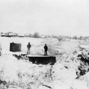 Two unidentified men standing by the Saratoga hot springs with snow cover, September 25, 1935. Courtesy Saratoga Museum collection, P1975.001.080, donated by Historic Reproductions by Perue.