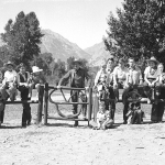 Larry Larom and dudes at a gate on the Valley Ranch southwest of Cody, 1930s. Note the "VR" configured into the gate, along with the ranch's brand, which shows also on the front of Larom's boots in the previous photo. Charles Belden photo, American Heritage Center.