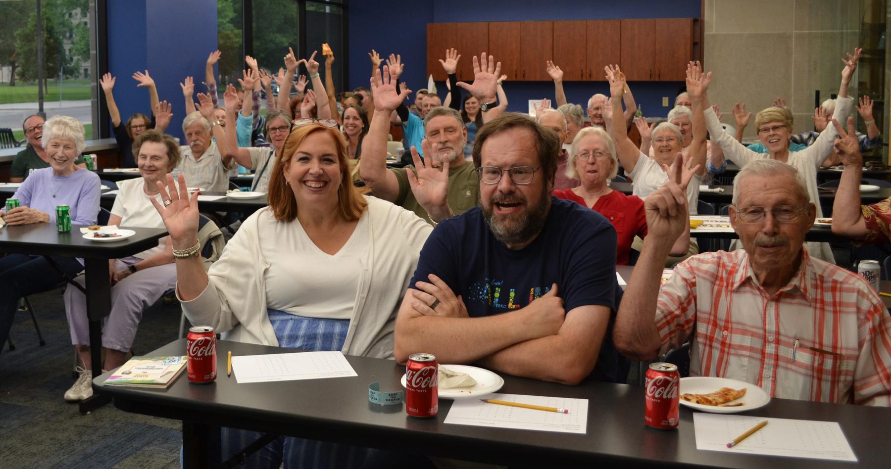 Celebrate Civic Season with a pizza party while you play trivia and learn some history. Classroom filled with people smiling and waving their hands in the air