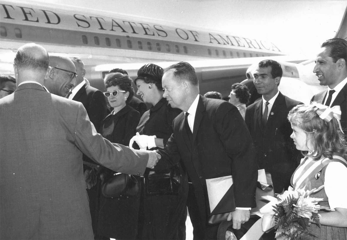 In September 1963 the king and queen of Afghanistan visited the University of Wyoming. At the Cheyenne airport, the king, Zahir Shah, in glasses, shakes hands with G. W. Arnold, director of the Afghanistan program at UW. At the center of the photo are Mrs. N. W. Hilston, wife of the dean of UW’s agriculture college; Mrs. Arnold, and Arnold. American Heritage Center, University of Wyoming. In September 1963 the king and queen of Afghanistan visited the University of Wyoming. At the Cheyenne airport, the king, Zahir Shah, in glasses, shakes hands with G. W. Arnold, director of the Afghanistan program at UW. At the center of the photo are Mrs. N. W. Hilston, wife of the dean of UW’s agriculture college; Mrs. Arnold, and Arnold. American Heritage Center, University of Wyoming.