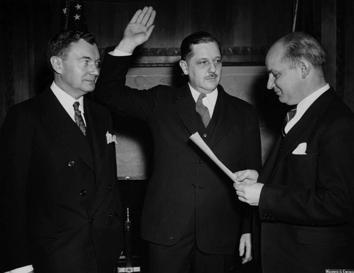 Thurman Arnold is sworn in as assistant U.S. attorney general in charge of the Justice Department’s Antitrust Division, March 22, 1938. On the left is U.S. Solicitor General Robert H. Jackson; on the right is Homer Cummings, attorney general. Arnold is in the middle. American Heritage Center. Thurman Arnold is sworn in as assistant U.S. attorney general in charge of the Justice Department’s Antitrust Division, March 22, 1938. On the left is U.S. Solicitor General Robert H. Jackson; on the right is Homer Cummings, attorney general. Arnold is in the middle. American Heritage Center.