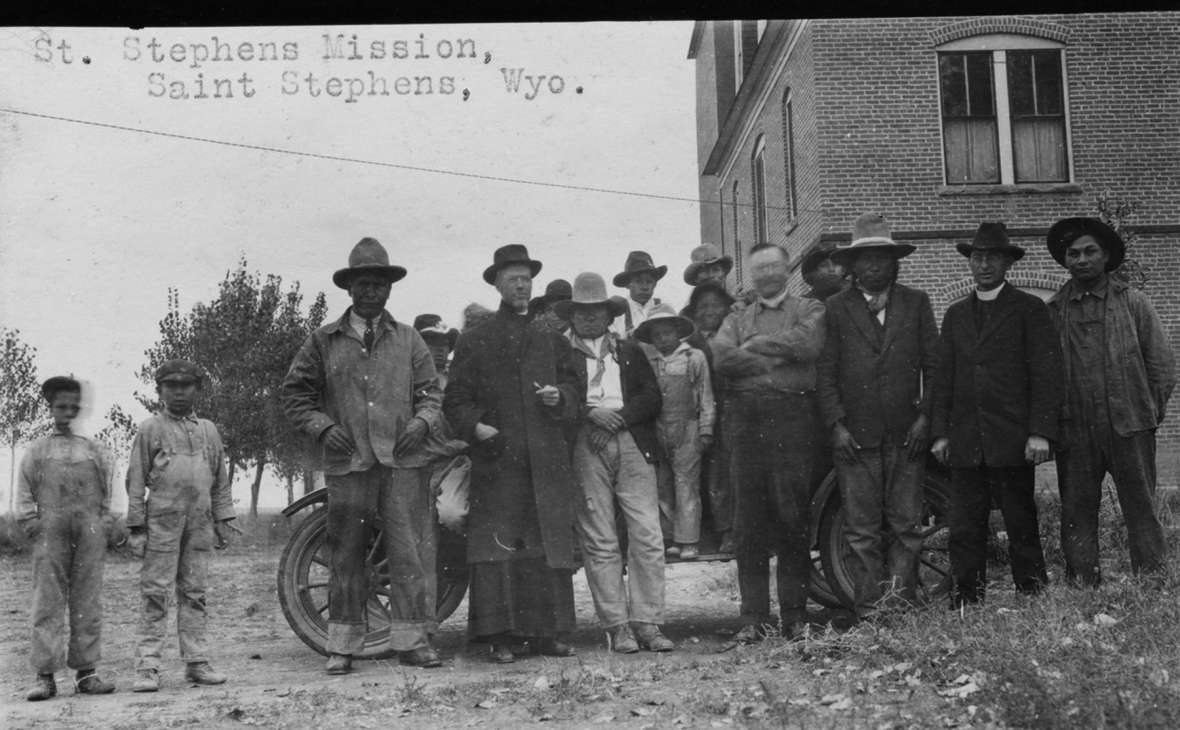 In the late 1880s, Roman Catholic Jesuit priests founded a mission school, which served mostly Arapaho children, at St. Stephens on the eastern side of the reservation. Here, two priests and others on the mission grounds, around 1920. Children boarded at the school until 1939. American Heritage Center.