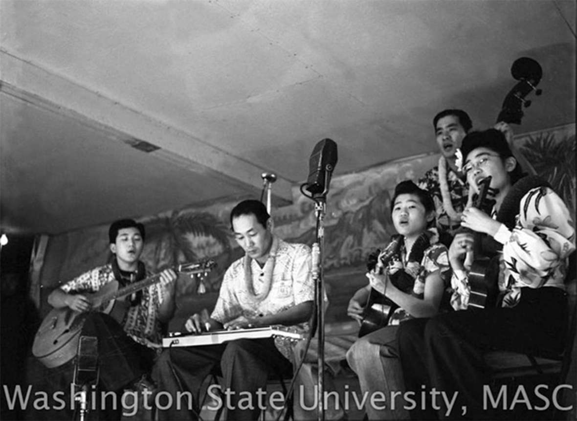 In 1942, Alfred Tanaka offered Hawaiian music instruction to Japanese-Americans interred at the Heart Mountain War Relocation Center near Cody, Wyo. A USO lounge at the camp presented a variety of music to departing servicemen including Hawaiian music on steel guitar and ukulele. The Surf Riders, a resident quartet featuring Alpha Tanaka, George Kobayashi, Jiro Suenake, and Jim Morioka were popular at the camp, playing here for the camp's parent-teachers council. Washington State Libraries. 