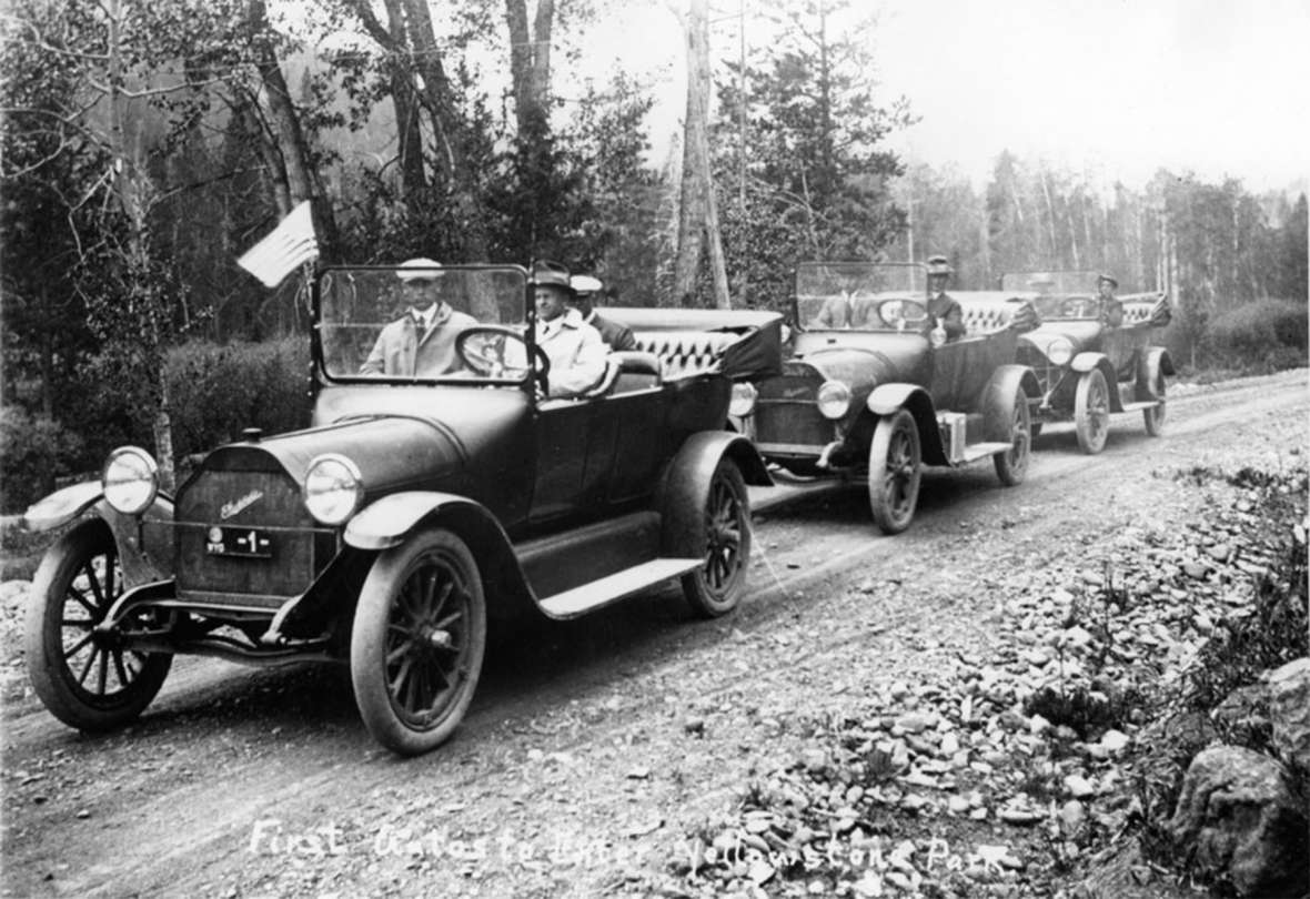 Good Roads Movement promoters Jake Schwoob and Gus Holm, in the front car here, were in the caravan of the first cars to enter Yellowstone, 1915. Growth in auto travel to national parks was one of the main drivers behind the naming of national highways in the 1910s and ‘20s, when most of them were still dirt. Park County Archives. Good Roads Movement promoters Jake Schwoob and Gus Holm, in the front car here, were in the caravan of the first cars to enter Yellowstone, 1915. Growth in auto travel to national parks was one of the main drivers behind the naming of national highways in the 1910s and ‘20s, when most of them were still dirt. Park County Archives.