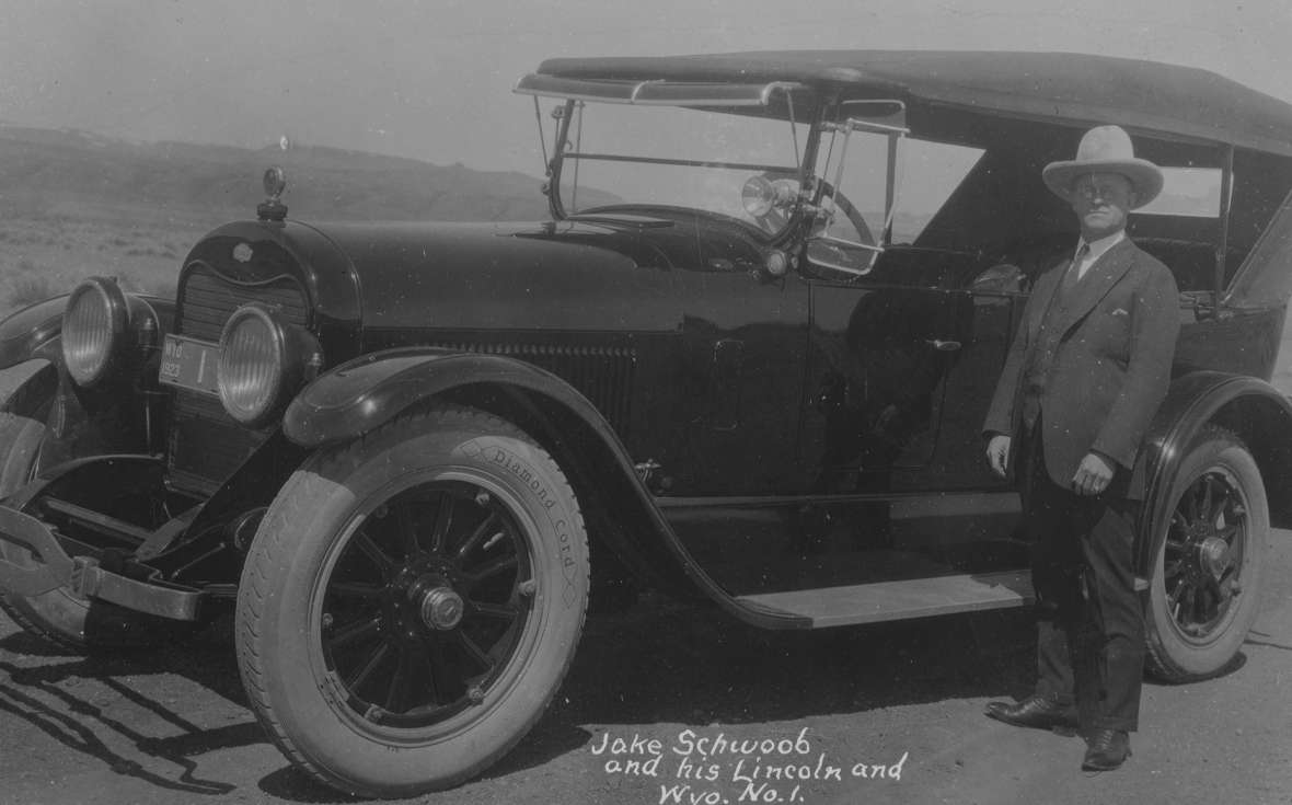 Good roads promoter Jake Schwoob of Cody owned one of Wyoming’s first car dealerships, and developed the county-based numbering system for Wyoming license plates. Here he is in 1923 by his Lincoln, bearing Wyoming license plate #1. American Heritage Center. Good roads promoter Jake Schwoob of Cody owned one of Wyoming’s first car dealerships, and developed the county-based numbering system for Wyoming license plates. Here he is in 1923 by his Lincoln, bearing Wyoming license plate #1. American Heritage Center.