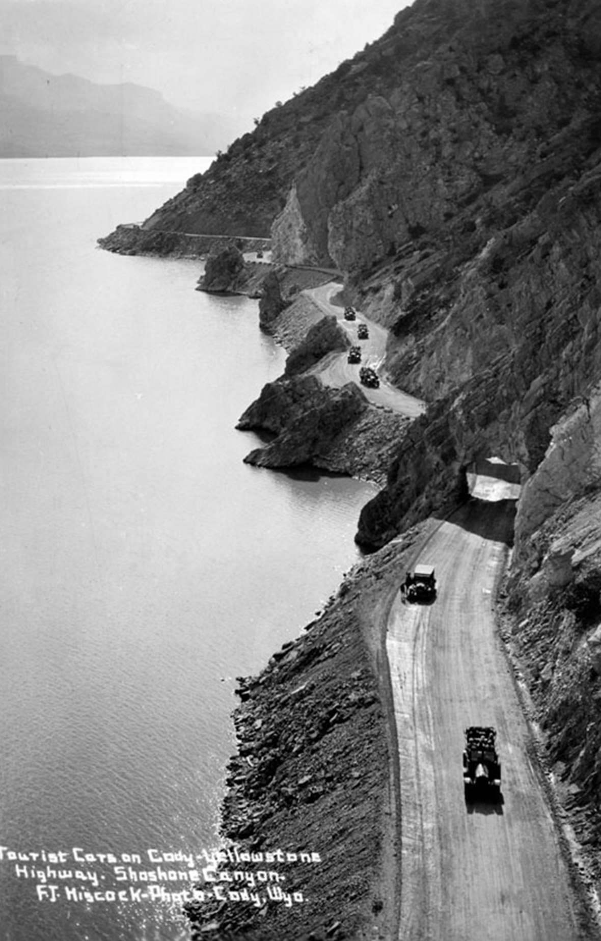 Tourist cars head toward Cody from Yellowstone Park on the road along the Buffalo Bill Reservoir. In the late 1920s the federal government began a system of numbered routes, as there were so many named highways the system was chaotic and confusing. While the new system lost romance, it gained efficiency. F.J. Hiscock photo, Park County Archives.