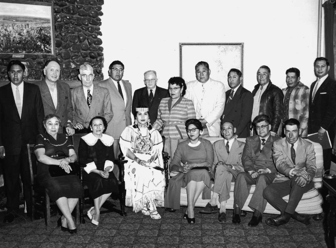 From early on, All American Indian Days leadership included a General Indian Committee. Standing, left to right: Black Beaver, Louis Tellier, Tom Harwood (vice chair), Peter Red Horn, Howard Sinclair (secretary), Ella McCarty, Martin Cross, Joe Medicine Crow, Tom Yellowtail, Jesse Old Man, Brummett Echohawk. Seated, left to right: Amy McCurdy, Mrs. Tom Harwood, Sandra May Gover (Miss Indian America IV), Matilda Grant, William Shakespeare (vice chair), Arthur Montiac, George Harris (general chairman). THE Wyoming Room, SCFPL.