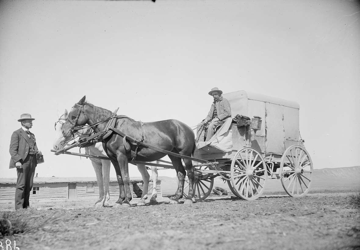 By the late 1890s, modest mud wagons like this one, with oil lamps and a two-horse team, were common on the Rawlins-Fort Washakie route. Bull Springs station, where this photo was taken in June 1897, was 27.5 miles northwest of Rawlins. Shown here are Dr. E.W. Allen and driver Dick Harrison. American Heritage Center.