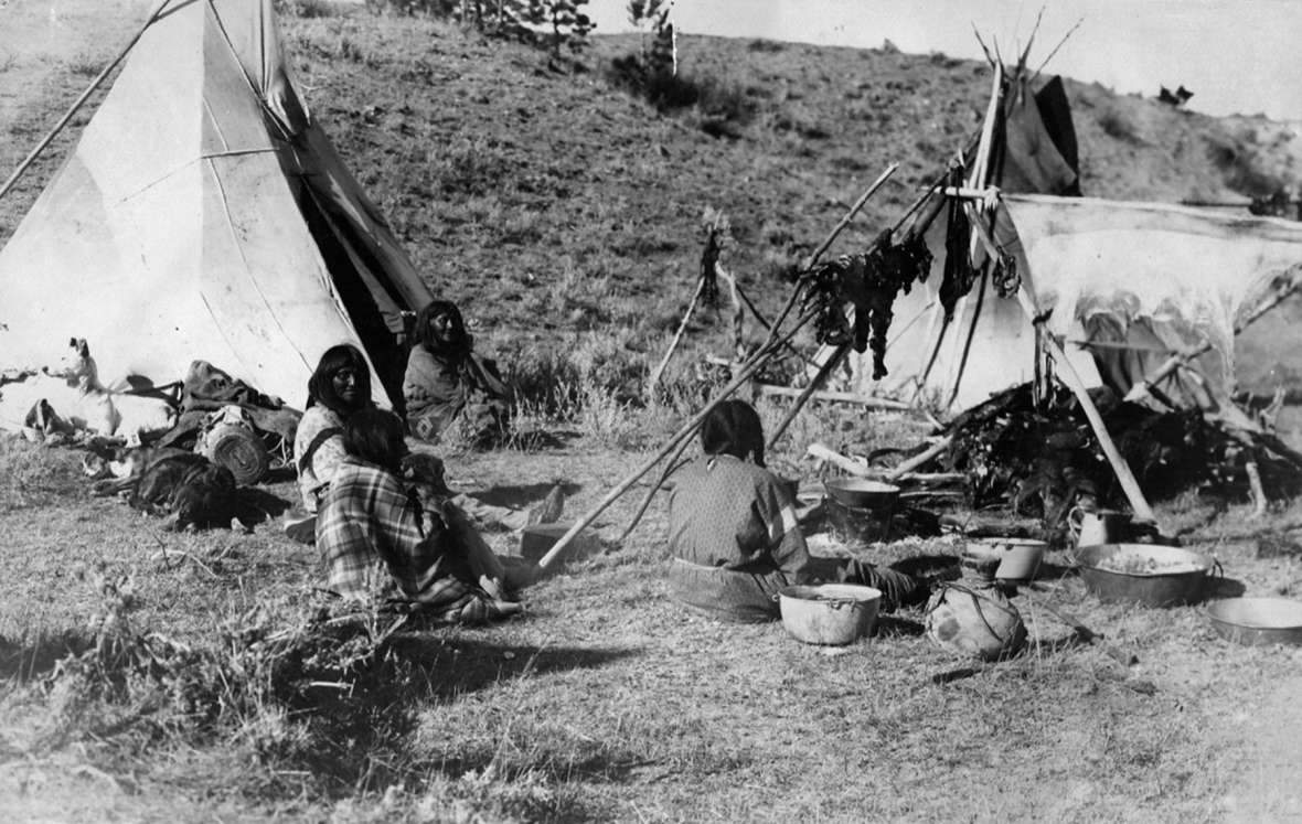 The White River Utes camped in late October 1906 on Powder River a short distance north of the Montana-Wyoming line. This view of one lodge and its residents also shows deer meat drying on a rack. T.W. Tolman photo, Campbell County Rockpile Museum.