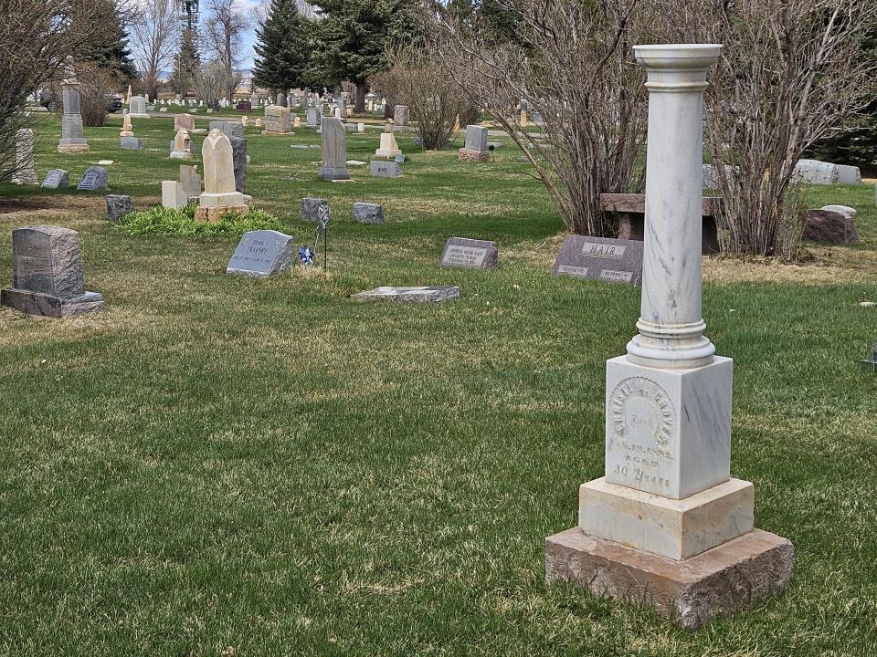 cemetery with marble headstone topped by a column in a green lawn