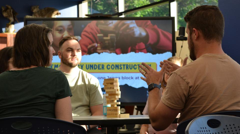 Three people conversing while playing Jenga.