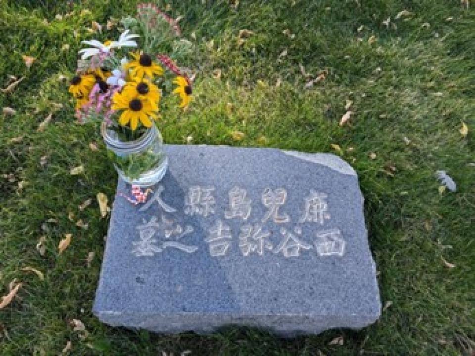 garvestone withe Japanese character engraved into the granite and a jar of sunflowers on the corner