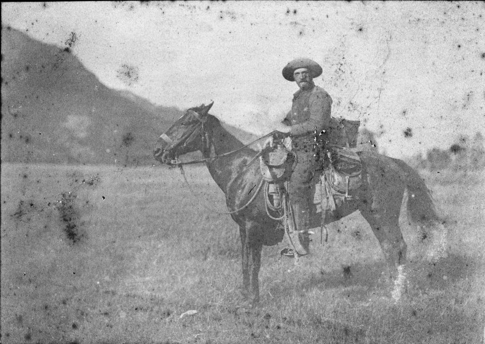 man on horseback posing in a wide meadow