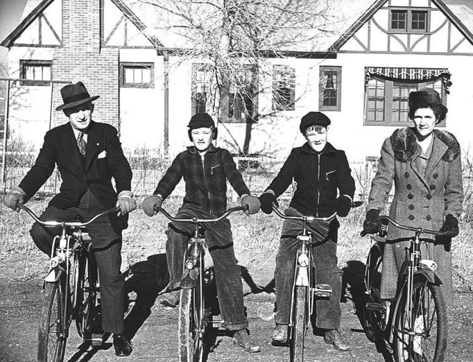 A man, two boys, and a woman pose on bikes facing the camera