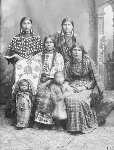 Kate Enos at top left, almost certainly at the same sitting as in the first photo. With her are her sisters, Louisa Enos Wesaw, Mary Enos Rabbittail, and Emma Enos Lewis. The baby in the cradle board is thought to be Antoine Weed, and the little girl standing, Sousanna Weed. Both are Mary Enos Rabbittail’s children. American Heritage Center via Sweetwater County Historical Museum. Kate Enos at top left, almost certainly at the same sitting as in the first photo. With her are her sisters, Louisa Enos Wesaw, Mary Enos Rabbittail, and Emma Enos Lewis. The baby in the cradle board is thought to be Antoine Weed, and the little girl standing, Sousanna Weed. Both are Mary Enos Rabbittail’s children. American Heritage Center via Sweetwater County Historical Museum.