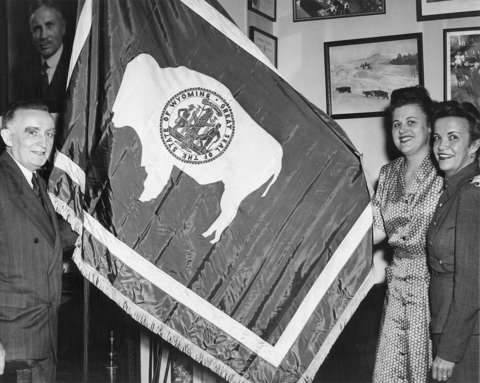 Wyoming’s U.S. senator Joseph O’Mahoney, left, and two staffers, one of them probably Margaret Cordiner Vendel, in O’Mahoney’s office in the 1940s. Above the senator’s head is a portrait of Senator, formerly Governor John B. Kendrick, who had signed the flag design into state law in 1917. In this version, the bison faces the pole— by that time the standard design. Wyoming State Archives. Wyoming’s U.S. senator Joseph O’Mahoney, left, and two staffers, one of them probably Margaret Cordiner Vendel, in O’Mahoney’s office in the 1940s. Above the senator’s head is a portrait of Senator, formerly Governor John B. Kendrick, who had signed the flag design into state law in 1917. In this version, the bison faces the pole— by that time the standard design. Wyoming State Archives.
