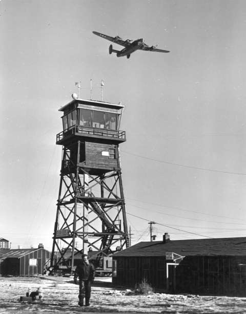 The U.S. Army Air Base in Casper opened in 1942 to train bomber crews. Here, a B-24 flies above the control tower. Casper College Western History Center.