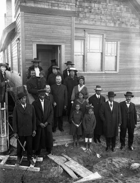 Parishoners in front of the joint Second Baptist-A.M.E. Church of Rock Springs April 1922. Although the pastor is unidentified, he appears in other photos with members of the Second Baptist congregation. The church was built in 1921. Sweetwater County Historical Museum.