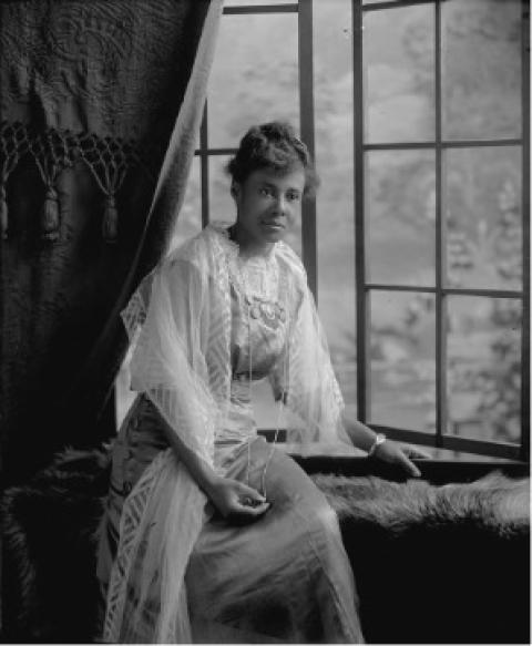 Like many Wyoming women, DeMarge (Thompson) Troliver became involved in her community and charitable organizations. In the 1930s she served as president to the Wyoming Association of Colored Women’s Clubs. Black oman ina long dress with a lace shawl poses in front of an open window