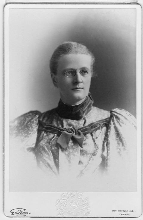 This photo of Agnes Wergeland was most likely taken sometime while she was a docent in history and non-resident instructor at the University of Chicago fromal portrait of woman wearing glasses and a puffy-sleeved floral dress with velvet collar and bow