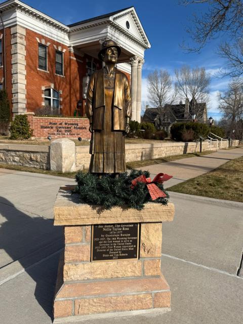 Bronze statue of a woman, set on a pedestal in front of an imposing building