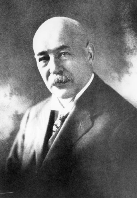 formal balck and white portrait of a moustached man in a suit