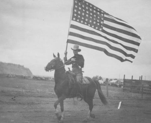 cowboy on horseback carries an American flag