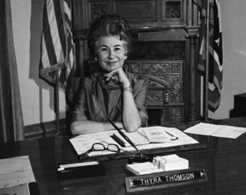 Thyra Thomson at her desk, smiling