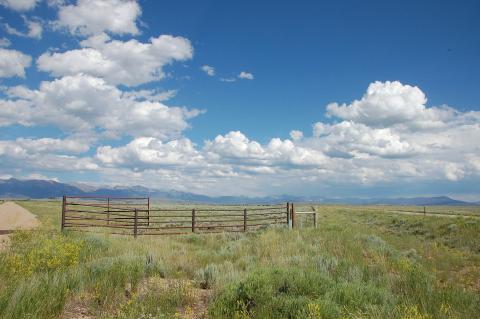 open grassland with a small corral in the foreground and mountains in the far distance