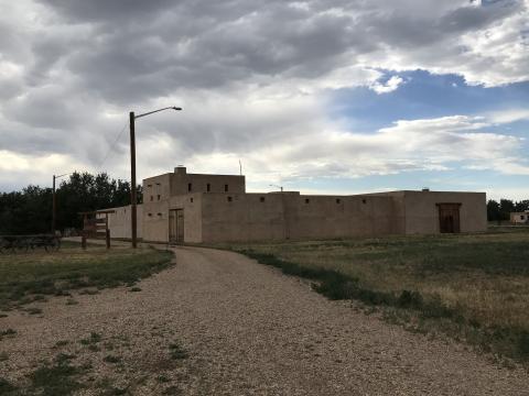 adobe walled fort set back from a gravel driveway