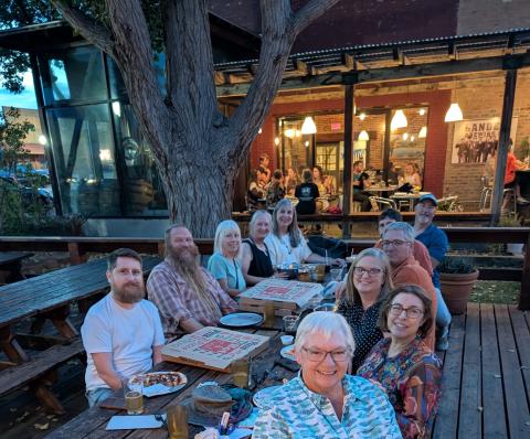 Group of adults sitting around a picnic table smiling