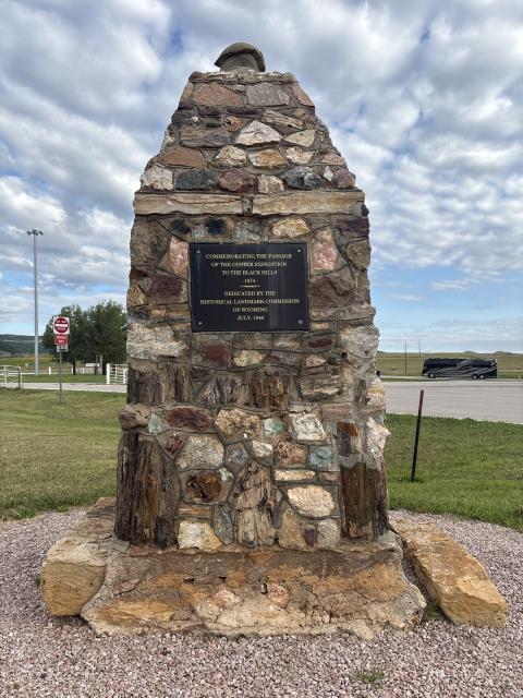 stone column with bronze plaque embedded; plaque text reads "Commemorating the passage of the Custer Expedition to the Black Hills 1874 / Dedicated by the Historical land Commission of Wyoming, July 1940